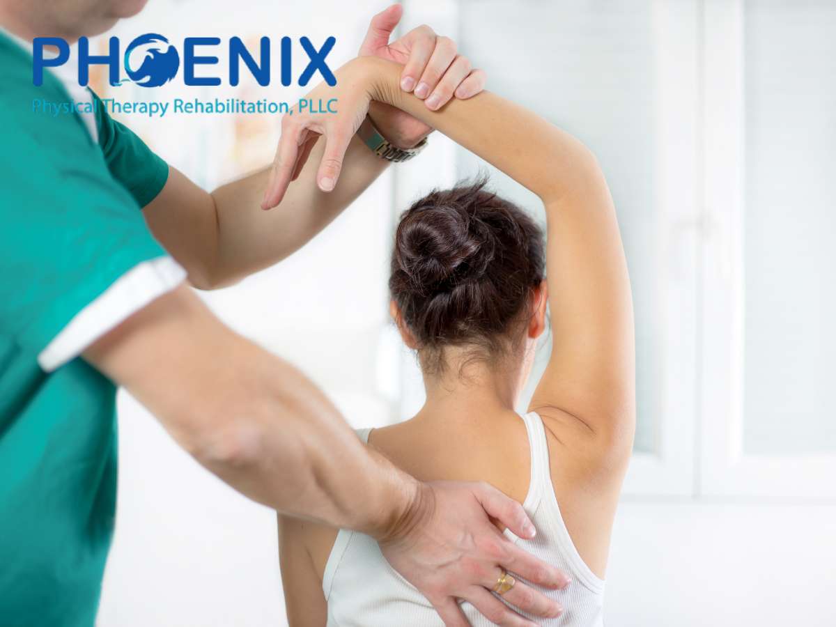 A Certified Physical Therapist at Phoenix Physical Therapy Rehabilitation, PLLC, assists a female patient with a shoulder exercise.