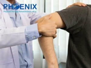 Therapist assisting a patient with arm movement at Phoenix Physical Therapy